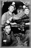 Three men in an underground shaft around a drill, wpH434